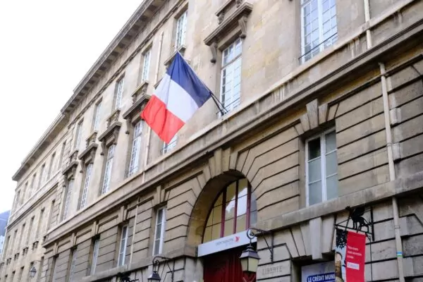 A french flag hangs from an old stone building.